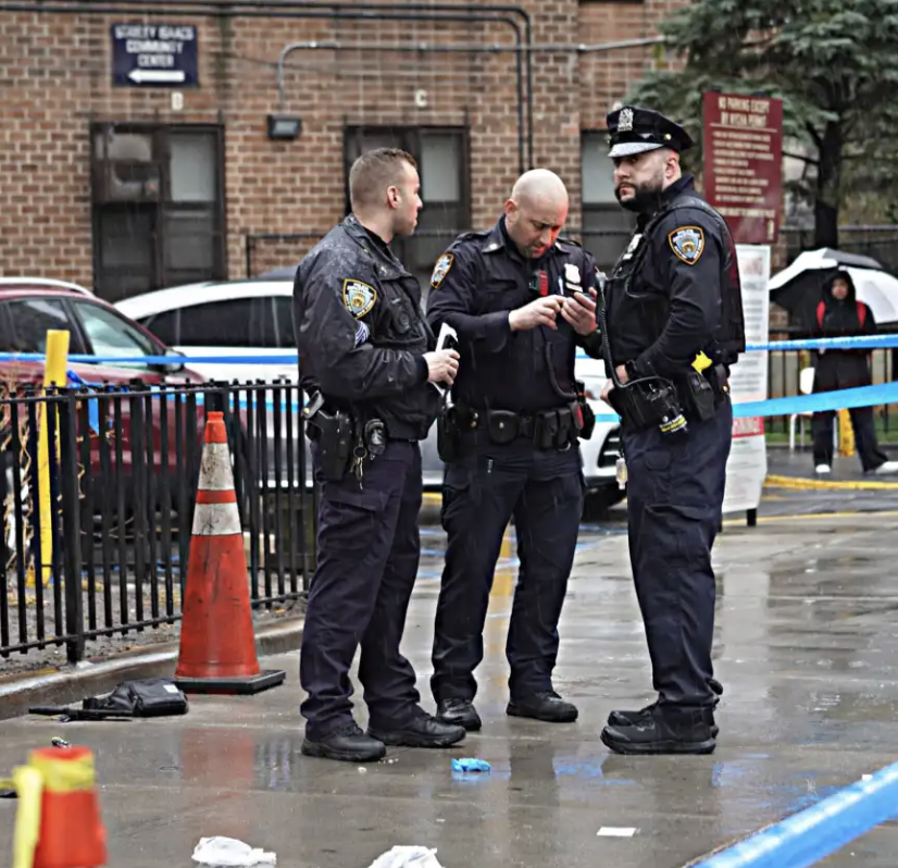 A police officer standing behind yellow crime scene tape outside a deli and a McDonald's at night